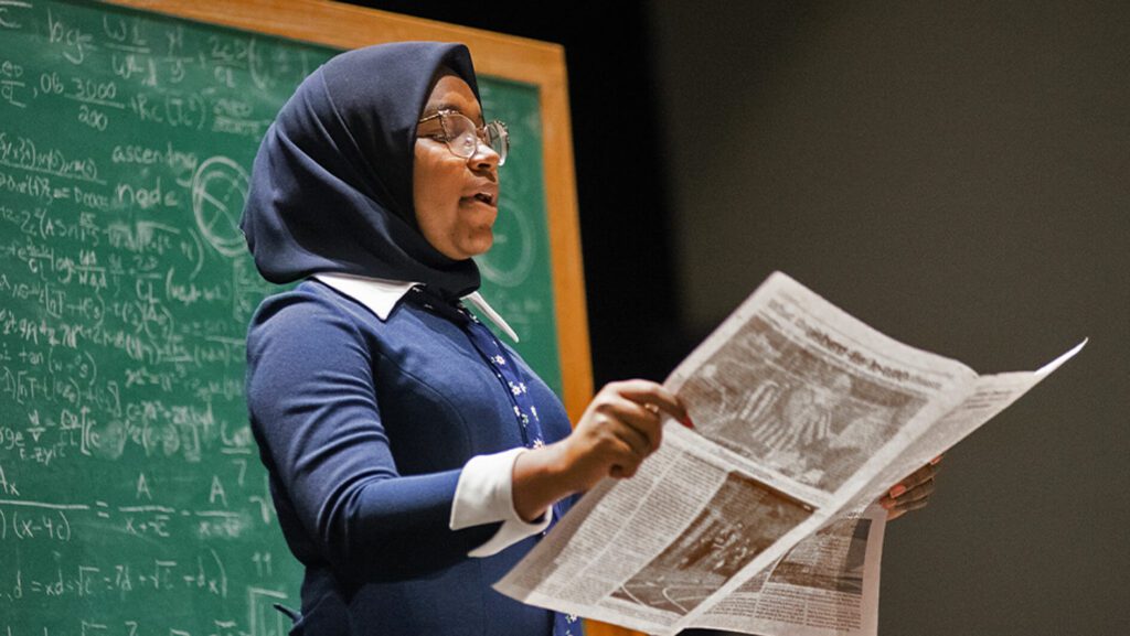 Young girl dressed up and reading a newspaper, performing in NHD contest.